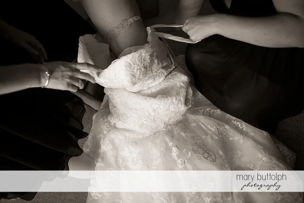 Close up shot of the bride's wedding gown being fixed by friends at the Inns of Aurora Wedding