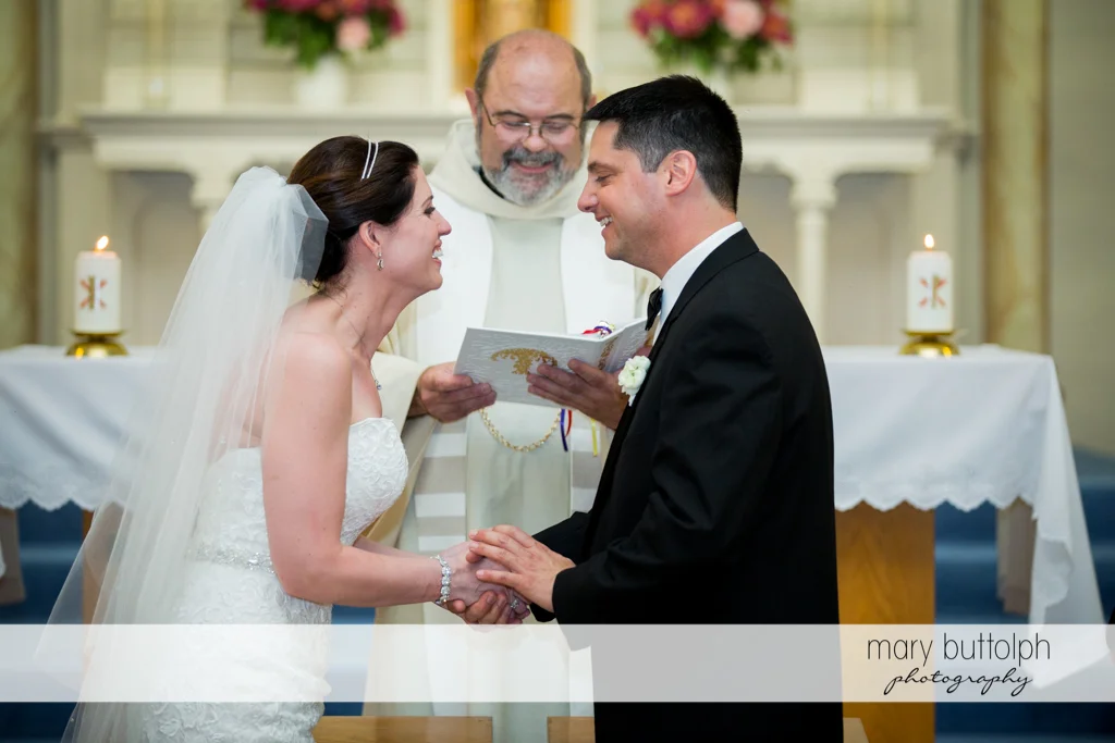 The couple face each other in front of the priest at the Inns of Aurora Wedding
