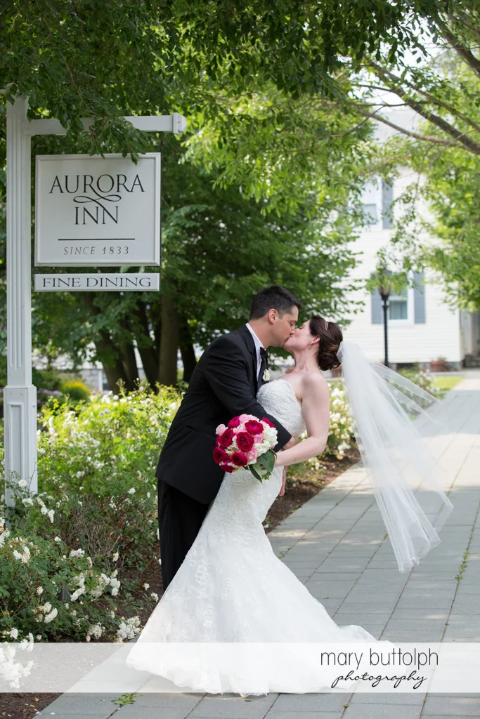Couple kiss in front of the sign at the Inns of Aurora Wedding