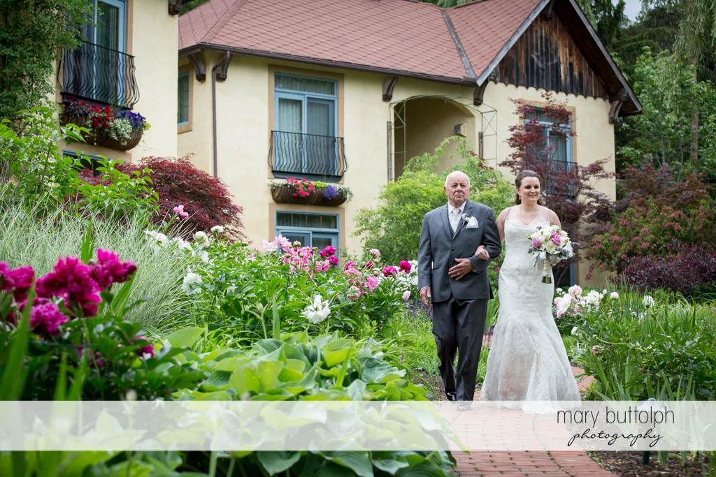 Bride is escorted by her father to the wedding venue at the Mirbeau Inn & Spa Wedding