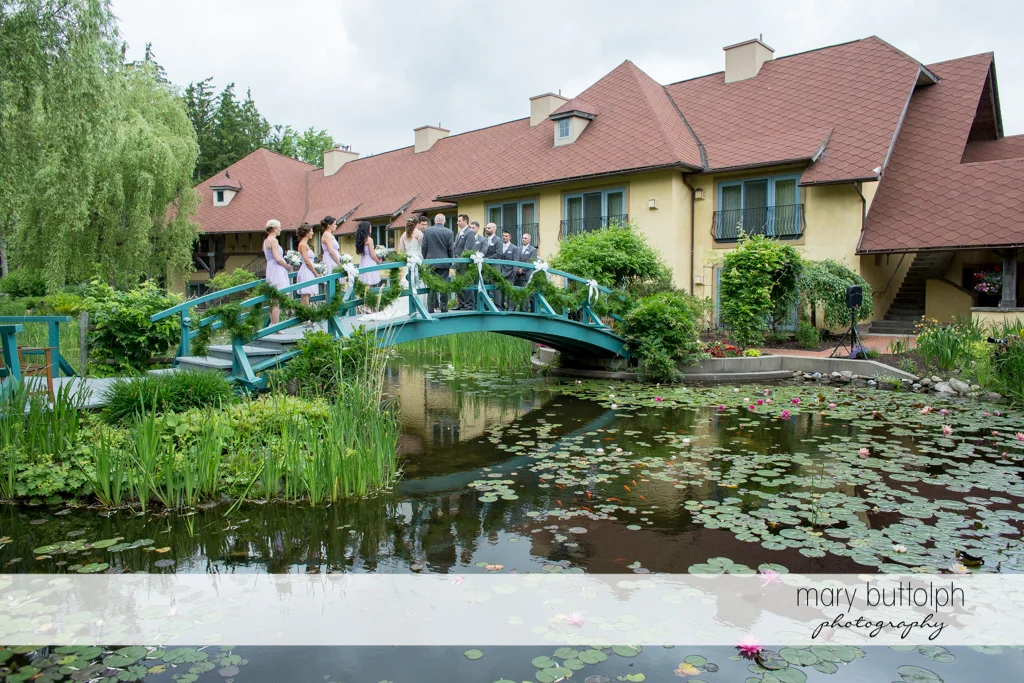 Another long shot of the wedding party on the wooden bridge at the Mirbeau Inn & Spa Wedding
