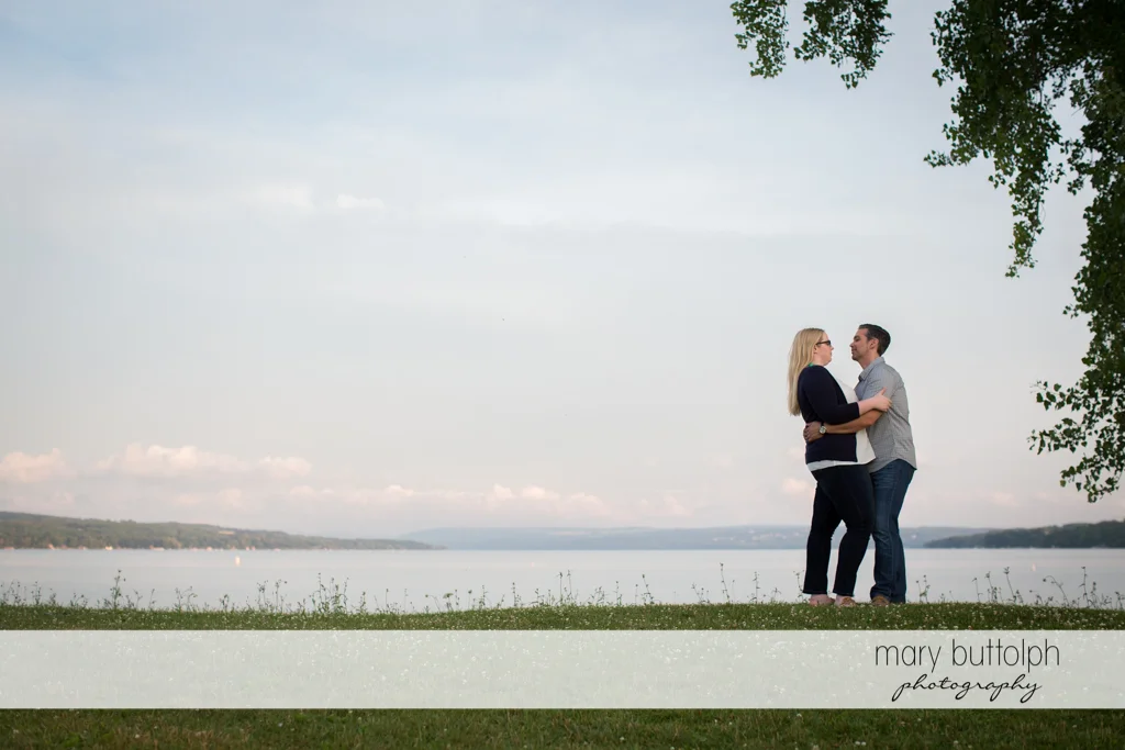 Couple embrace by the lake at Skaneateles Engagement