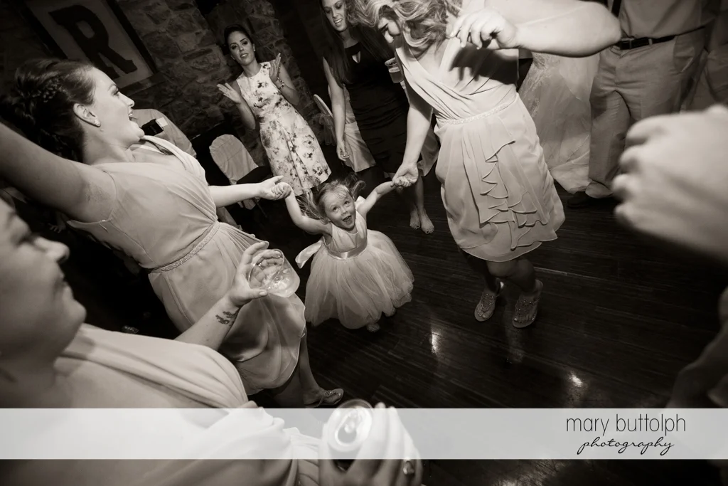 Guests dance with a young girl at the wedding venue at Arrowhead Lodge Wedding