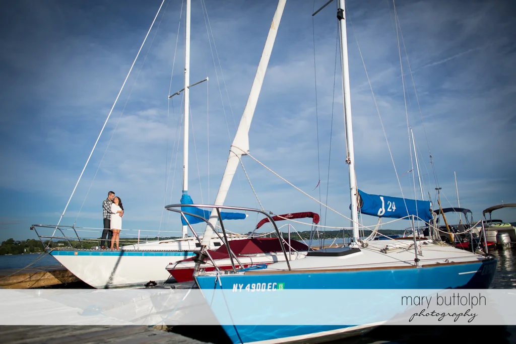 Couple pose in front of sailboats at Skaneateles Country Club Engagement