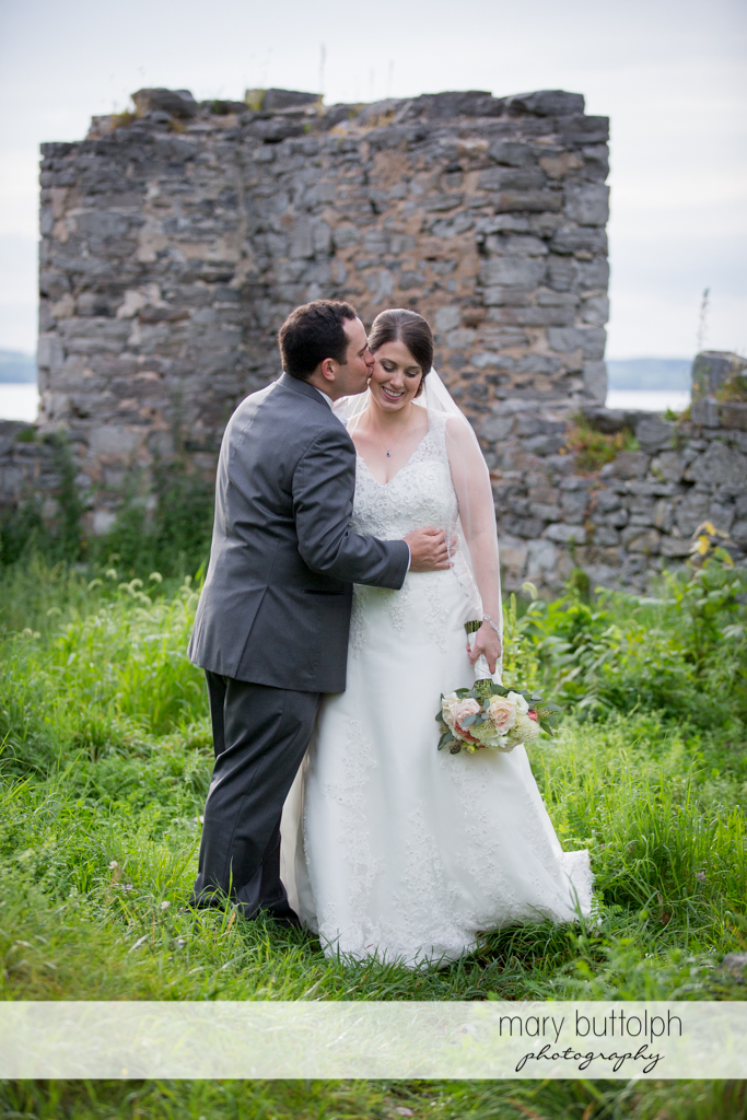 Groom kisses the bride in front of the ruins at the Inns of Aurora Wedding