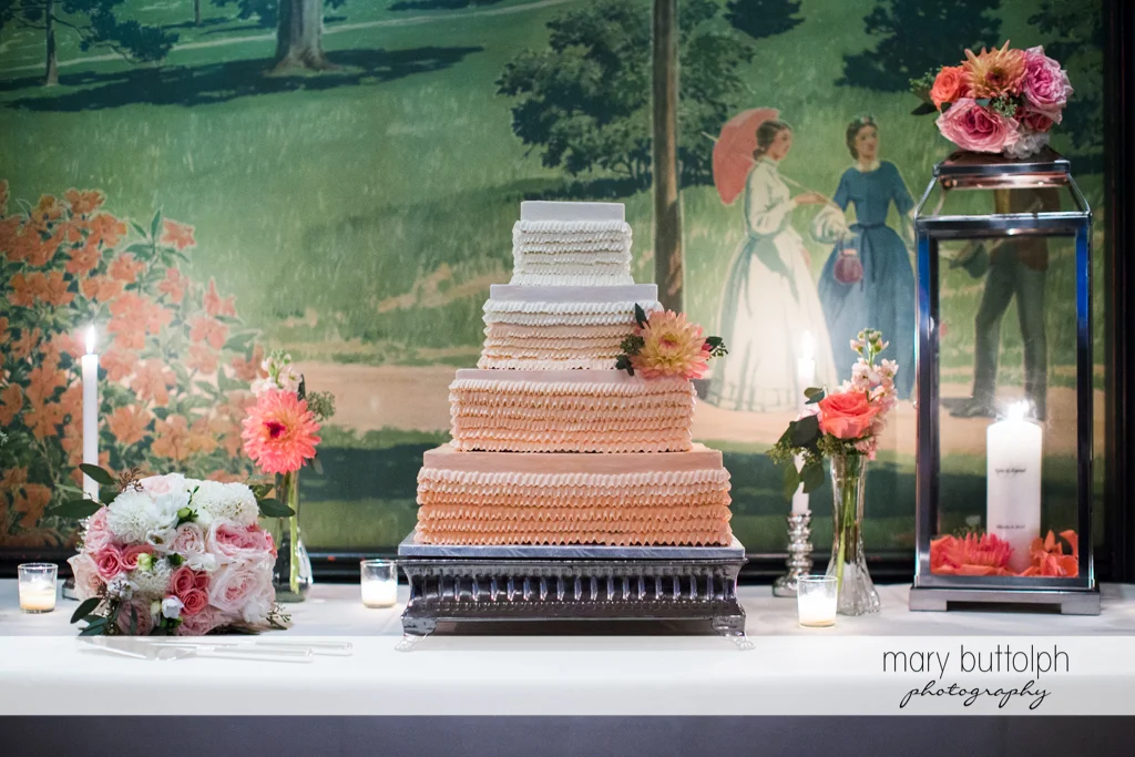 Couple's wedding cake sits on a table in front of a huge painting at the Inns of Aurora Wedding