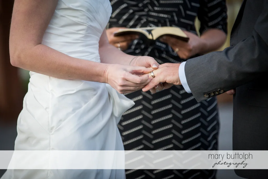 Bride slips on the groom's wedding ring during the garden wedding at Anyela's Vineyards Wedding