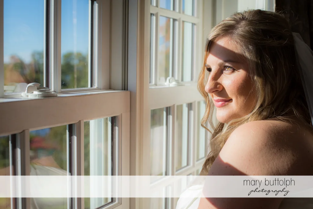 Bride looks through the window at the Inns of Aurora Wedding