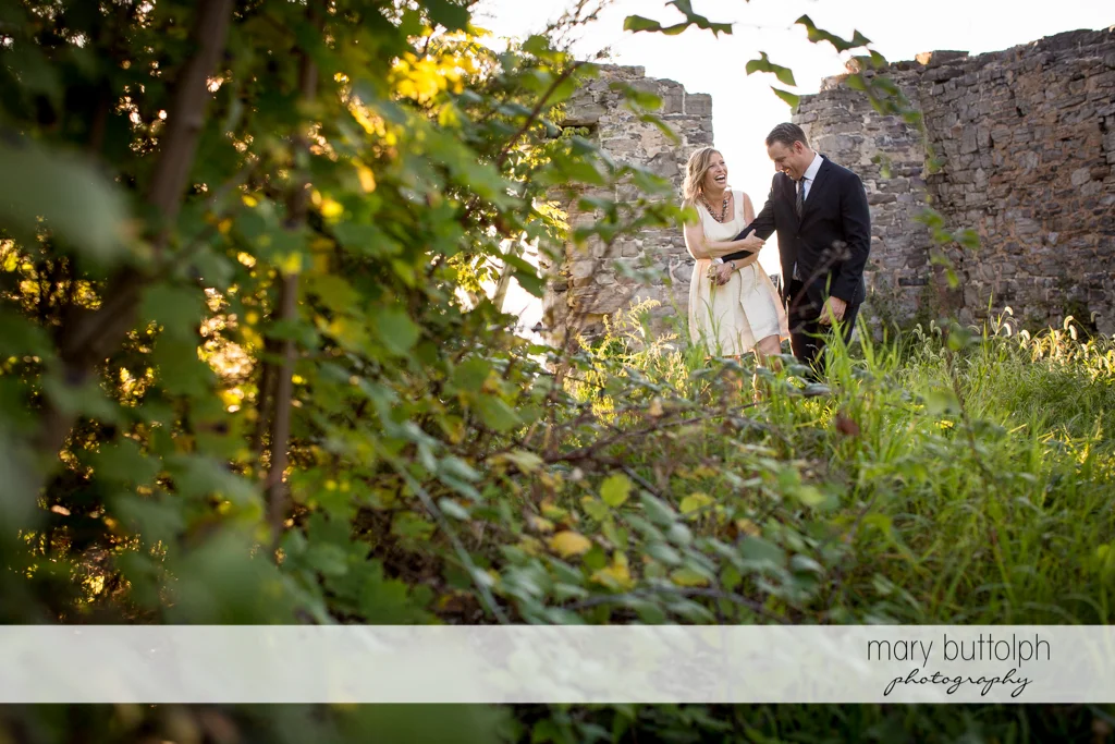 Couple stroll in the garden near a stone wall at the Inns of Aurora Engagement
