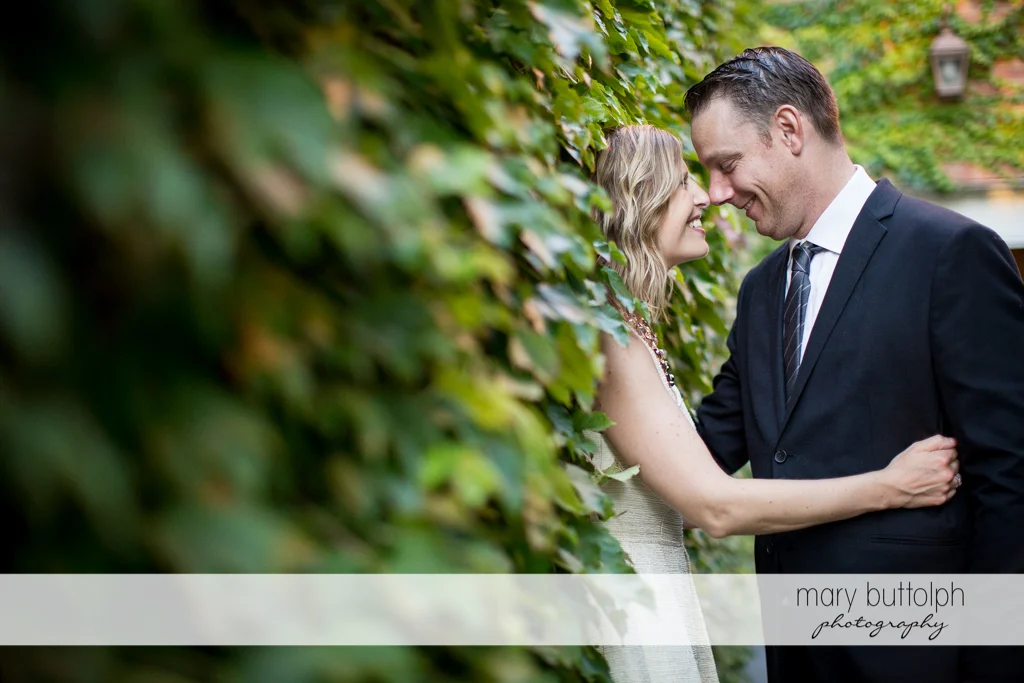 Couple pose near the plants in the garden at the Inns of Aurora Engagement
