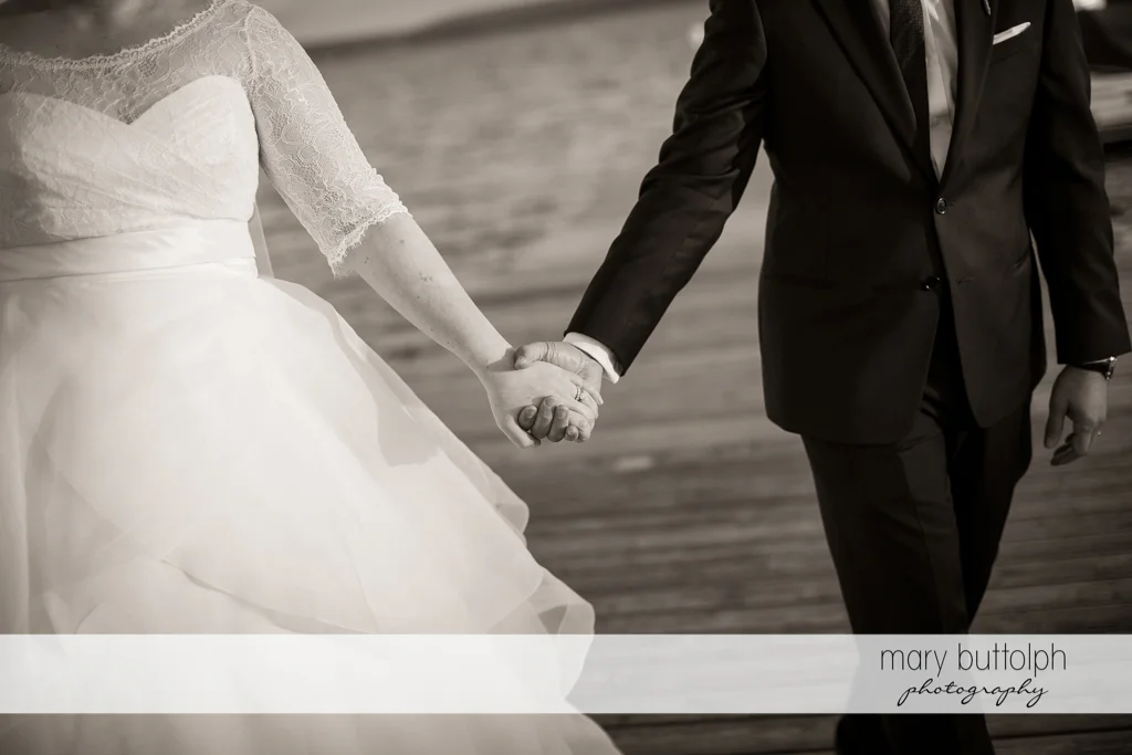 Couple hold hands near the lake at Skaneateles Country Club Wedding