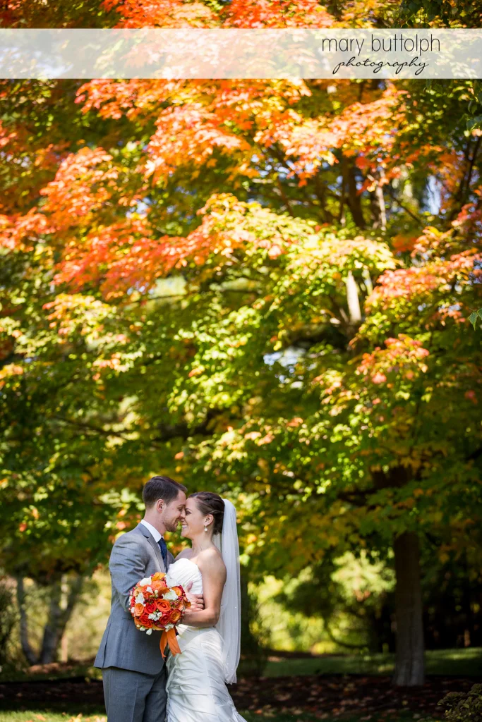 Couple rub noses in front of trees at Skaneateles Country Club Wedding