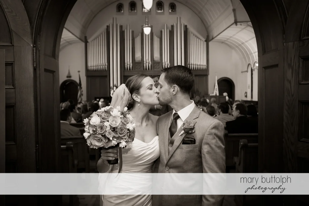 Couple kiss as they exit the church at Skaneateles Country Club Wedding