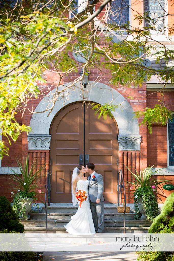 Couple kiss in front of the church at Skaneateles Country Club Wedding