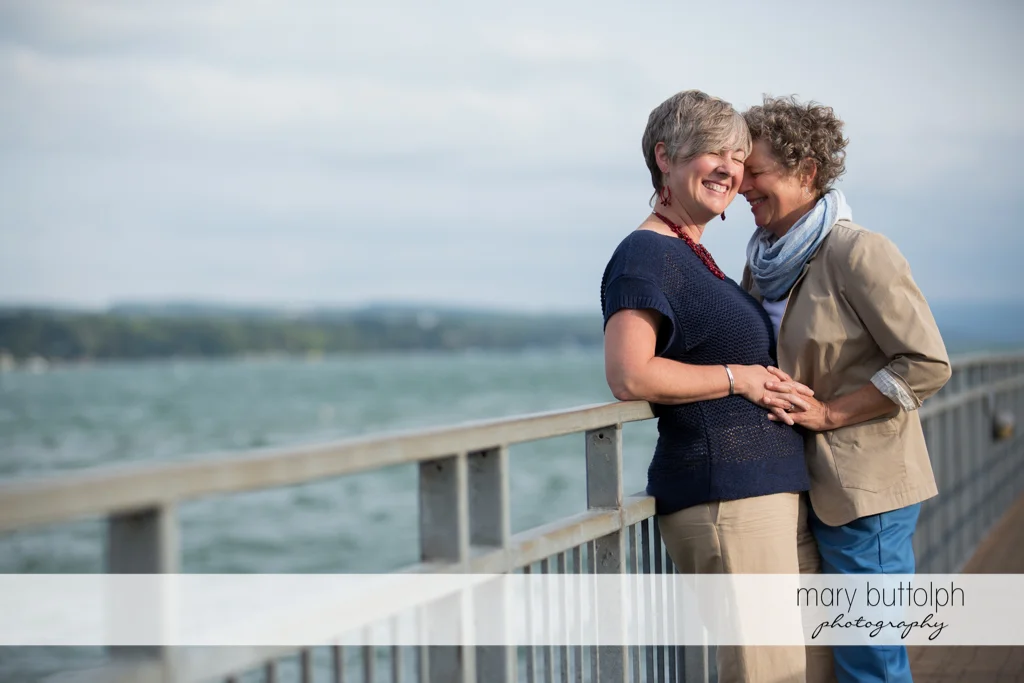 Same sex couple enjoy the lakeside view at Skaneateles Lake Engagement