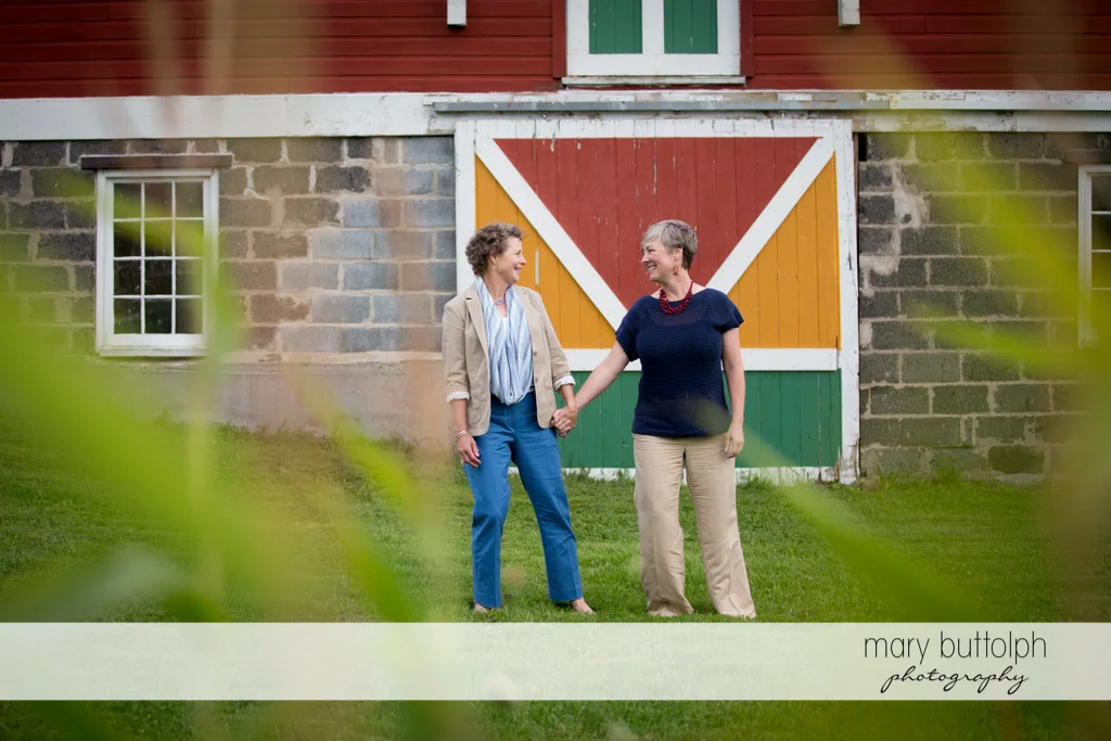 Same sex couple pose in front of an old house at Skaneateles Lake Engagement