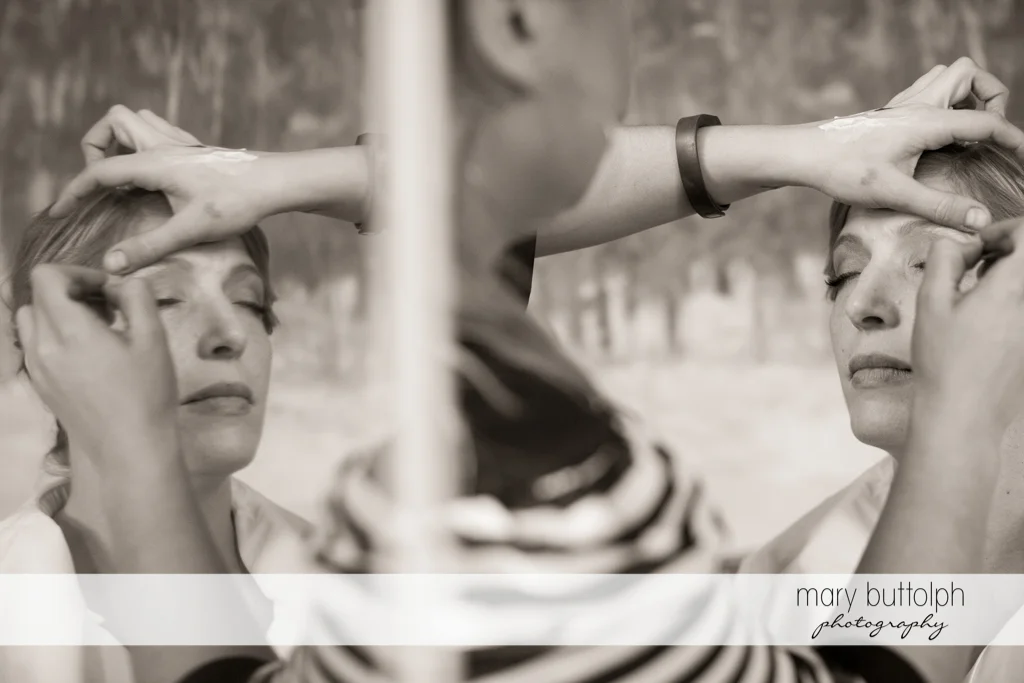 Bride's reflection appears in the mirror as she gets a makeover at Rowland House Wedding
