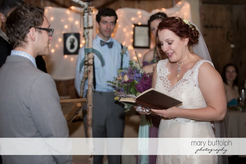 Bride reads from a book as the groom watches at Frog Pond Bed & Breakfast Wedding