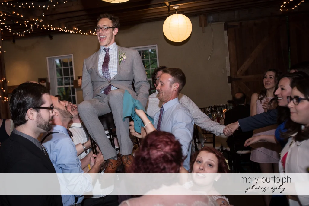 Groom is carried by groomsmen at Frog Pond Bed & Breakfast Wedding