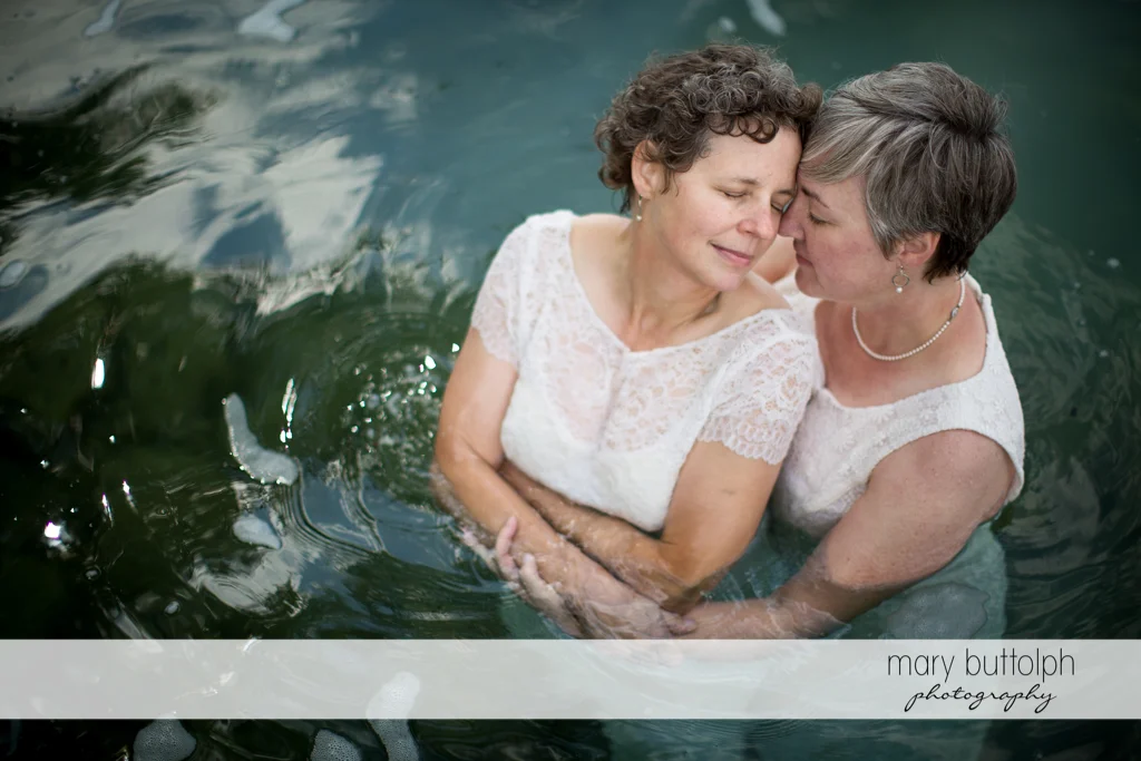 Same sex couple share a tender moment in the lake at Mandana Barn Wedding