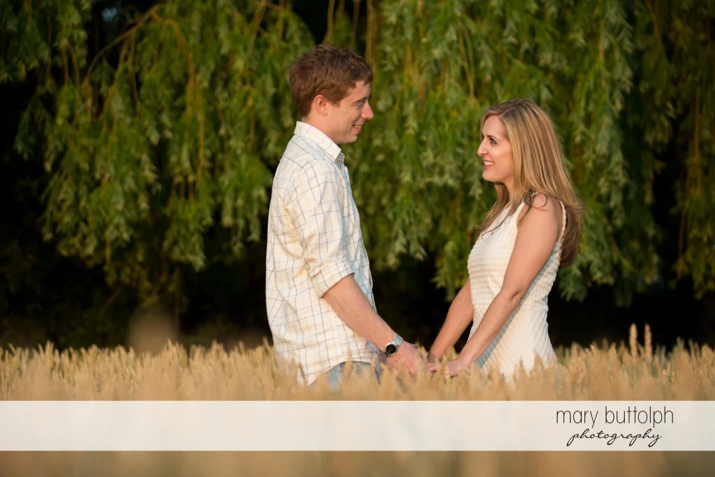 Couple hold hands in the middle of a wheat field at Skaneateles Engagement