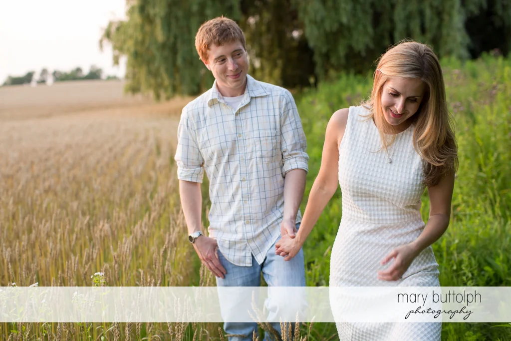 Couple stroll along a wheat field at Skaneateles Engagement