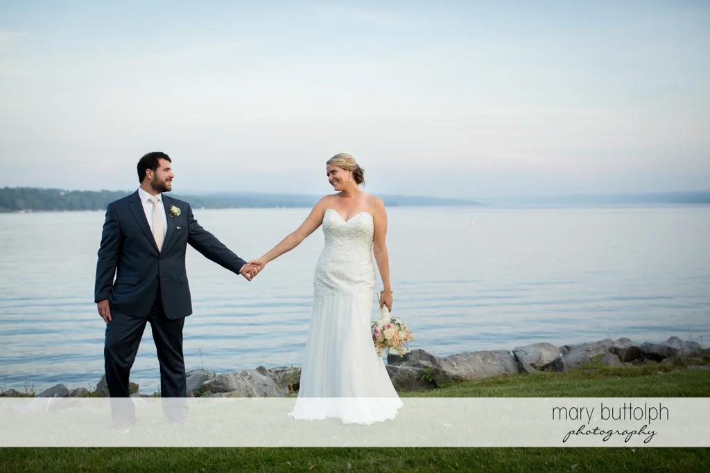 Couple hold hands by the lake at Emerson Park Pavilion Wedding
