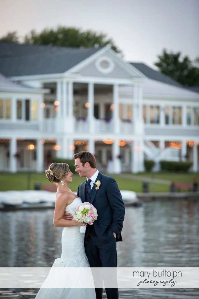 Couple stand in front of the wedding venue by the lake at Skaneateles Country Club Wedding