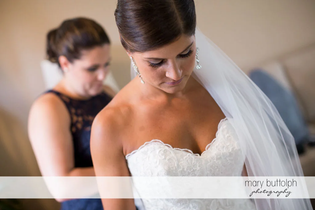 Bride waits patients as a friend fixes her wedding dress at Turning Stone Resort Casino Wedding
