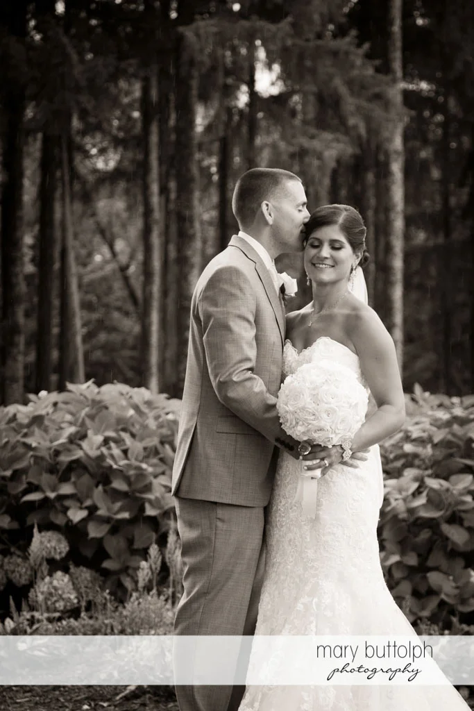 Groom kisses the bride in the woods at Turning Stone Resort Casino Wedding