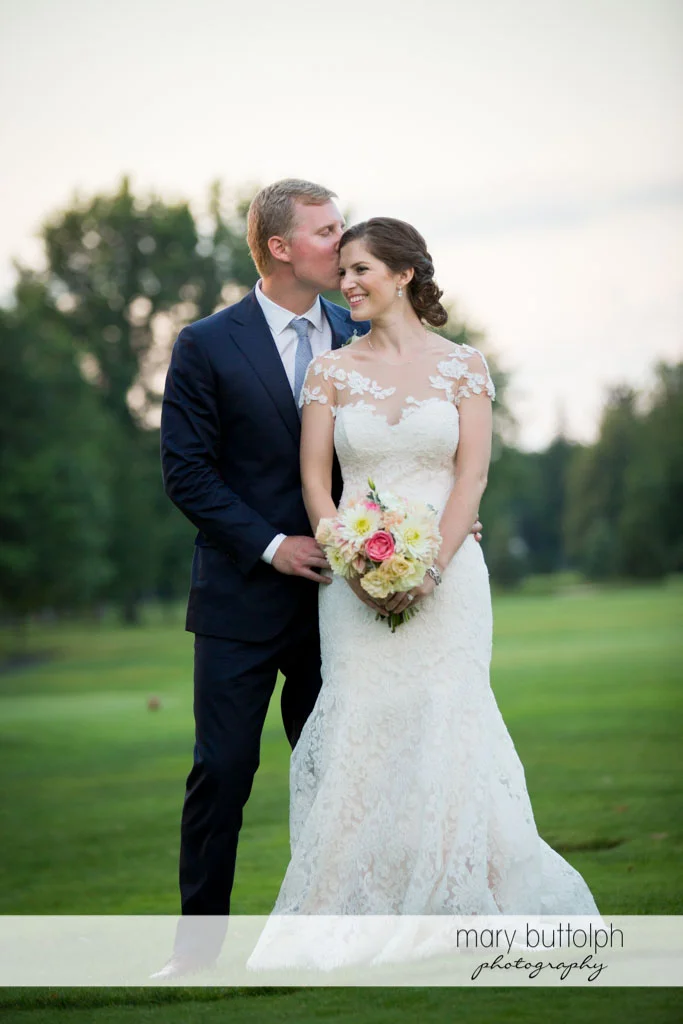 Groom kisses the bride in the garden at Skaneateles Country Club Wedding