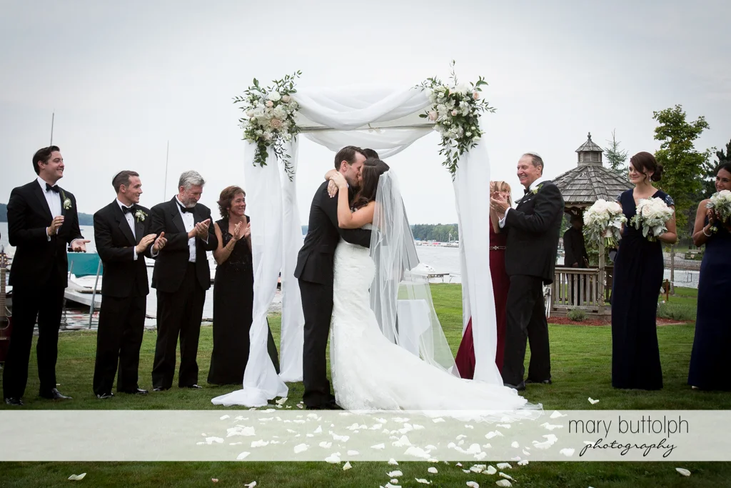 Couple kiss after the wedding as the wedding party looks on at the Brewster Inn Wedding