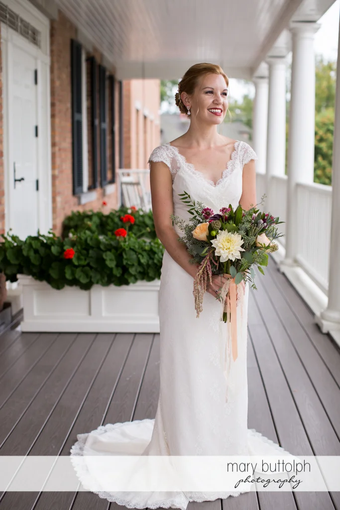 Bride with bouquet on the porch at the Inns of Aurora Wedding
