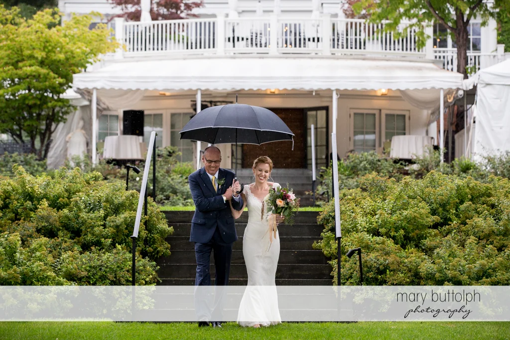 Bride's father shields his daughter from the rain at the Inns of Aurora Wedding