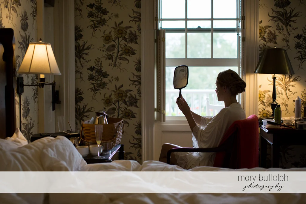 Bride looks at the mirror in her room at the Inns of Aurora Wedding