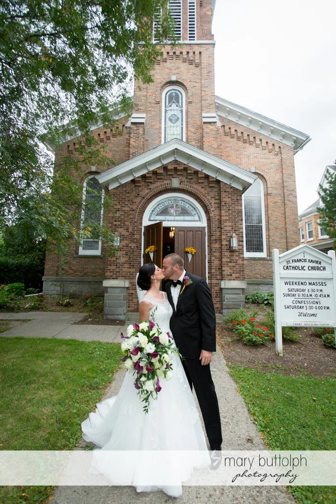 Couple kiss in front of the church at Anyela's Vineyards Wedding