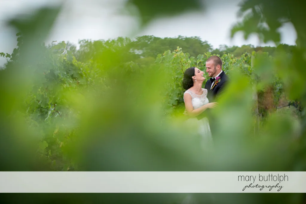 Couple as seen through the leaves of grapevines at Anyela's Vineyards Wedding