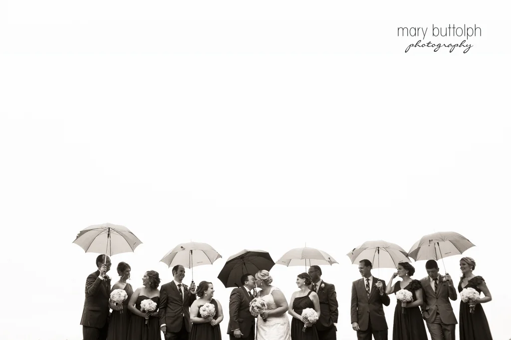 Umbrellas shield the wedding party from the rain at the Lodge at Welch Allyn Wedding