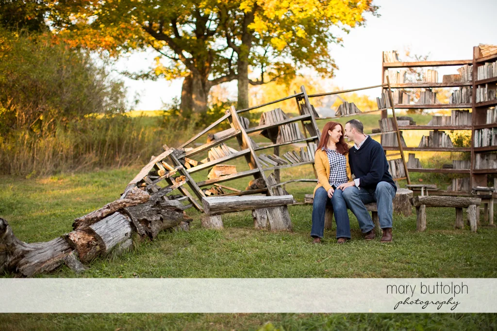 Couple sit in front of natural bookshelves in the park at Cazenovia Engagement
