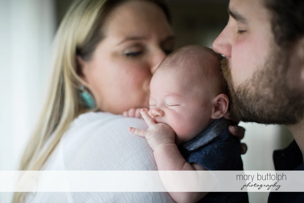 Couple kiss their baby at Syracuse Newborn