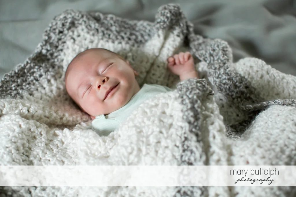 Baby smiles while sleeping in her crib at Syracuse Newborn