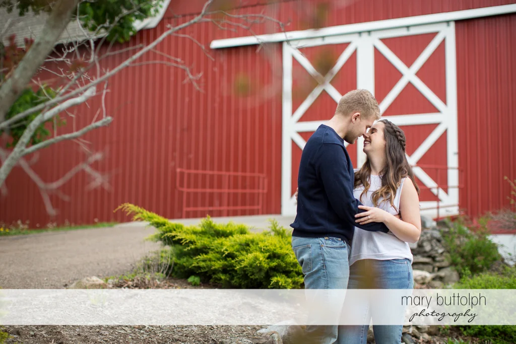Couple pose in front of the farmhouse at Hobbit Hollow Engagement