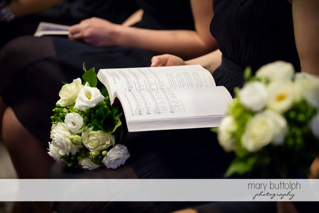 Guest with flowers reads the hymnal at Skaneateles Country Club Wedding
