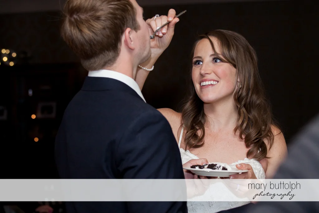 Bride feeds her husband with a slice of the wedding cake at Skaneateles Country Club Wedding