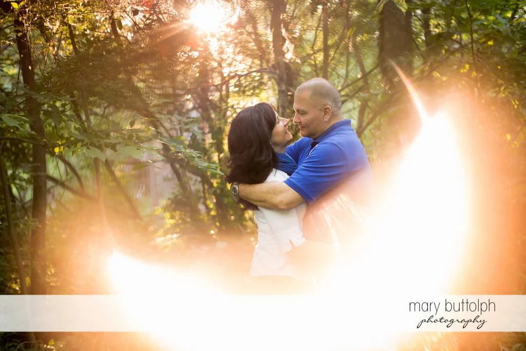 Couple embrace as sunlight surrounds them in the park at Skaneateles Engagement