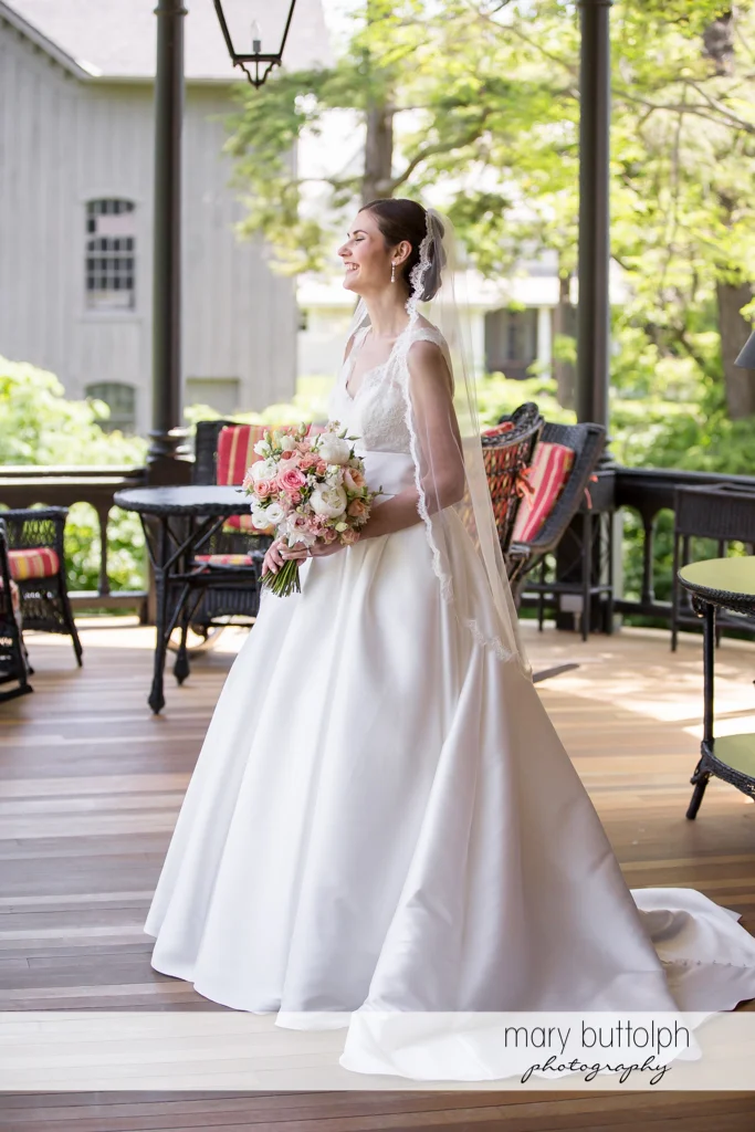 Happy bride with bouquet on the porch at the Inns of Aurora Wedding