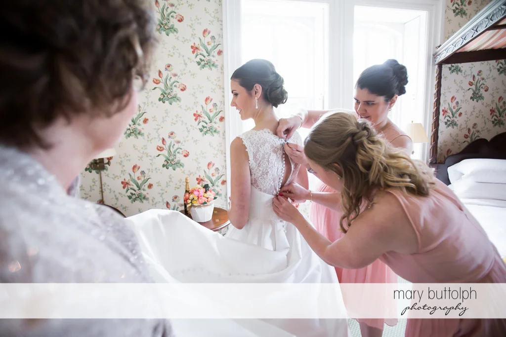 Brides get a little help from her bridesmaids who fix her dress at the Inns of Aurora Wedding