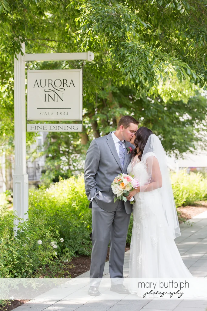 Couple kiss in front of an old sign at the Inns of Aurora Wedding