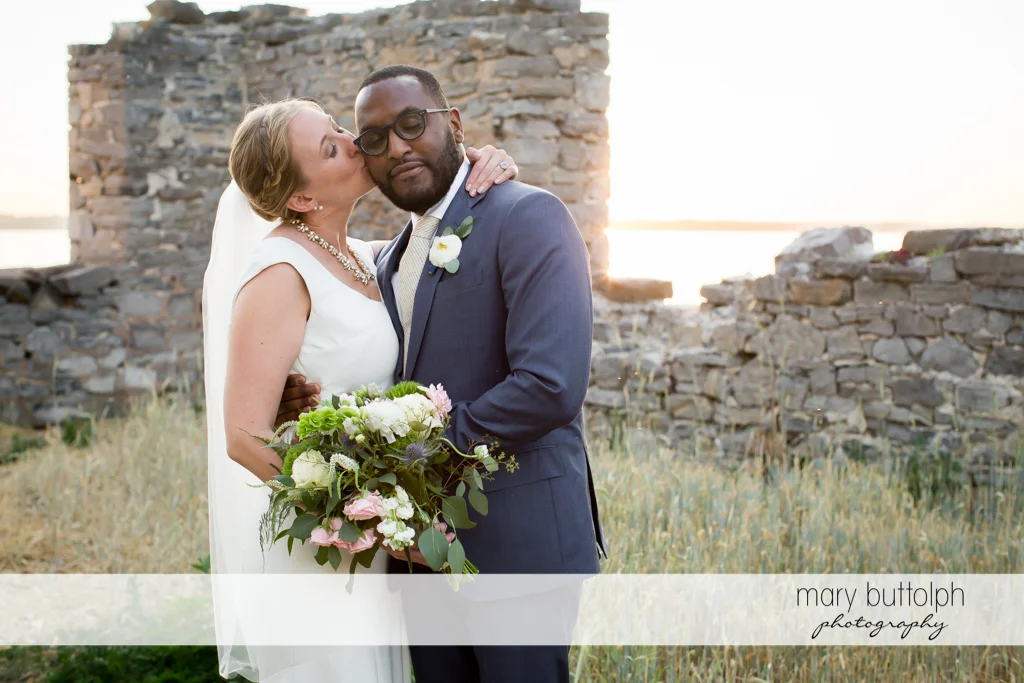 Bride kisses the groom in front of a brick structure at the Inns of Aurora Wedding