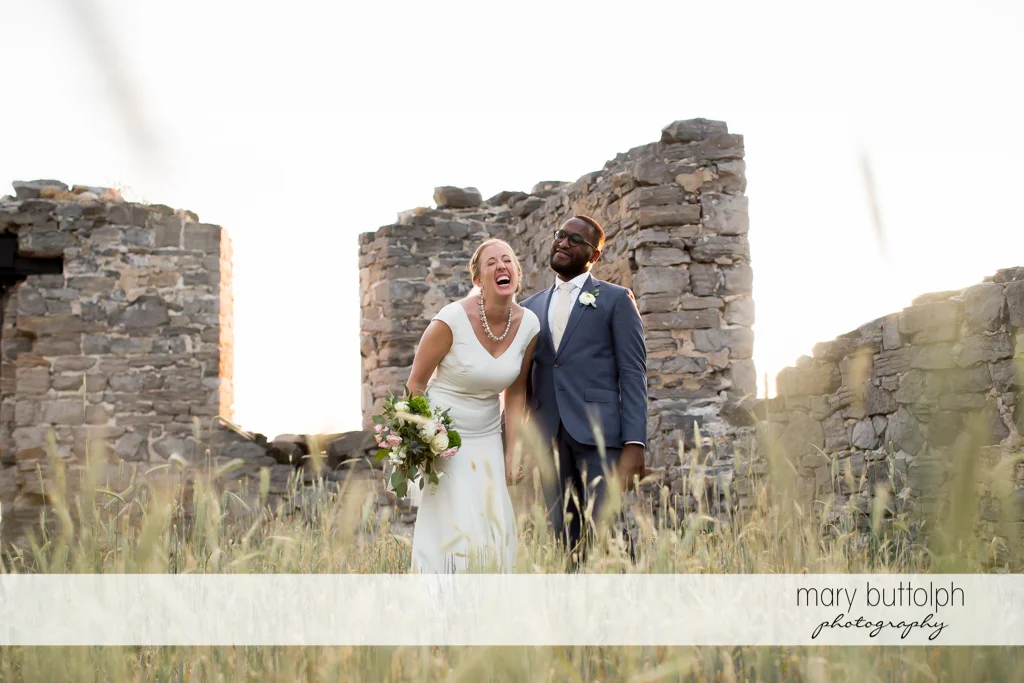 Couple share a good laugh in front of a brick structure at the Inns of Aurora Wedding